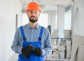 portrait-positive-handsome-young-male-builder-hard-hat-while-working-construction-site_255667-46964